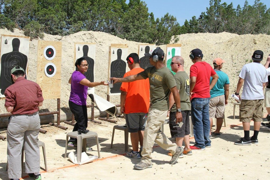Jason guiding a family member’s stance on the firing line as others look on.