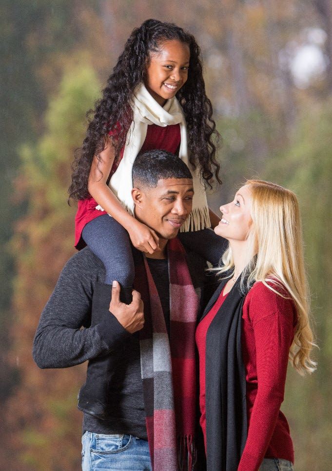 Jason carrying his daughter Solana on his shoulders beside Ellie in the fall.