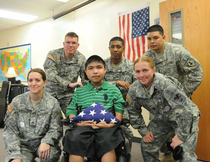 Jason and fellow soldiers gathered around a young Make-A-Wish recipient holding a folded American flag.