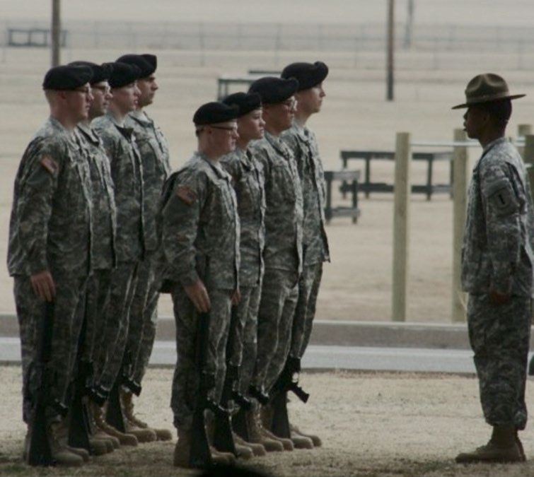 Jason in a drill sergeant’s campaign hat facing a formation of soldiers.