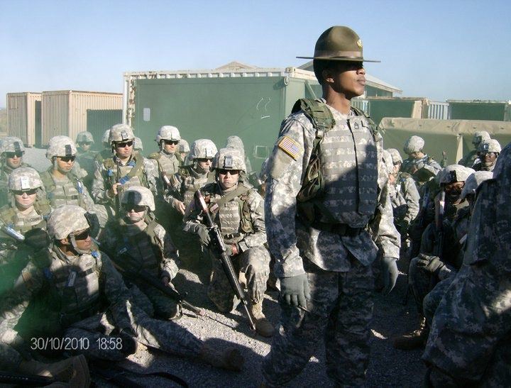 Jason in a drill sergeant’s hat and body armor standing among kneeling basic trainees.